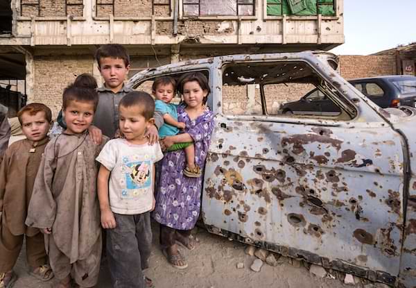 Children next to a bullet-ridden car